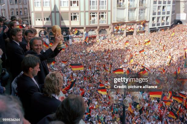 Thousands of jubilant people give the players of the German national soccer team an avid welcome waving flags and cheering on 09 July 1990 at the...