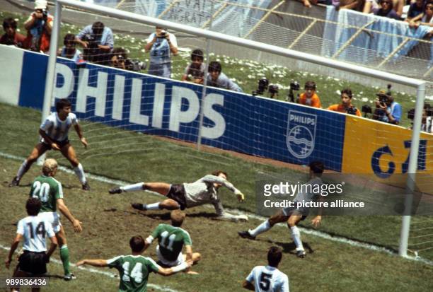 German forward Karl-Heinz Rummenigge manages to score the 1-2 goal as he falls to the ground while German defender Thomas Berthold raises his arms...