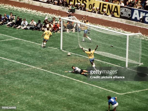 Italian goalkeeper Enrico Albertosi lies defeated on the pitch as the ball rolls back out of his goal. Brazilian scorer Carlos Alberto throws his...