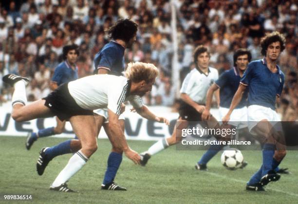 German forward Horst Hrubesch falls down together with an unidentified Italian defender. While fellow German forward Klaus Fischer is lurking for a...