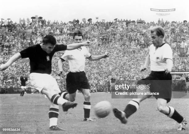 Hungarian goalgetter Ferenc Puskas kicks the ball before German player Werner Liebrich can block his shot while German forward Ottmar Walter comes...