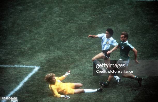 German goalkeeper Harald Schumacher rushes out of his goal to meet attacking Argentinian forward Jorge Burruchaga who, albeit being also attacked by...