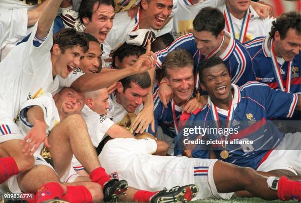 French midfielder Didier Deschamps sits next to French goalgetter Zinedine Zidane , slightly bend forward, while both cheer and laugh with the rest...