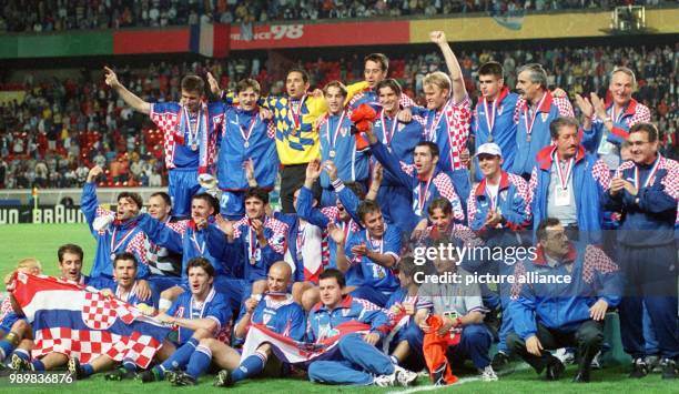 Players, trainers and assistants of the Croatian national soccer team jubilate and cheer as they pose for a group picture after winning the 1998...