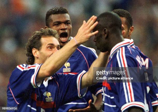 French defenders Laurent Blanc and Marcel Desailly run towards French defender Lilian Thuram and congratulate him after Thuram scored the 1-1...