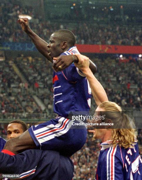 Carer carries on his shoulders the two-fold goalsocerer, jubilating French defender Lilian Thuram , across the pitch while French midfielder Emmanuel...