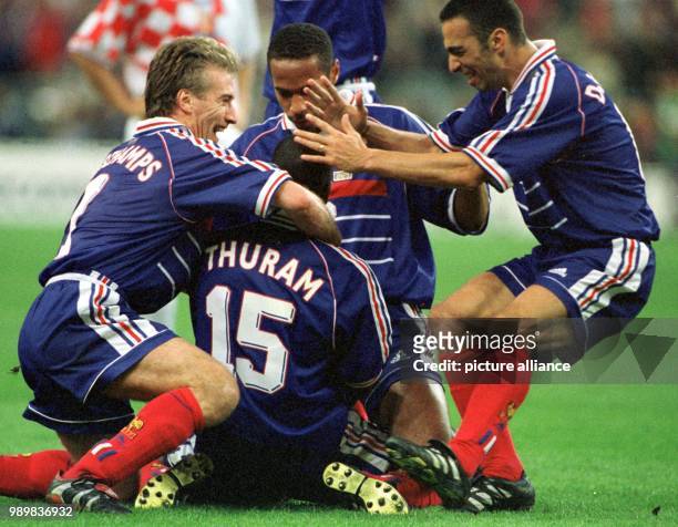 French team captain Didier Deschamps , forward Thierry Henry and midfielder Youri Djorkaeff gather around goal scorer Lilian Thuram in order to...