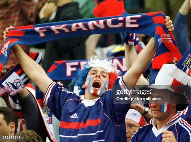 French supporter holds up his fan scarf and frenetically cheers on his team during the World Cup semi-final game France against Croatia in Saint...