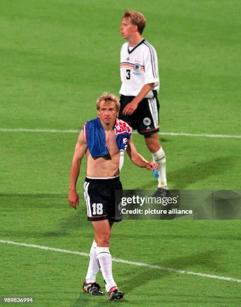 German forward Juergen Klinsmann and midfielder Joerg Heinrich leave disappointed the pitch after the 1998 World Cup quarter final Germany against...