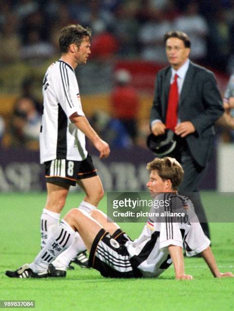 German midfielder Michael Tarnat sits disappointed on the pitch while German defender Lothar Matthaeus, also not very happy looking, walks past...