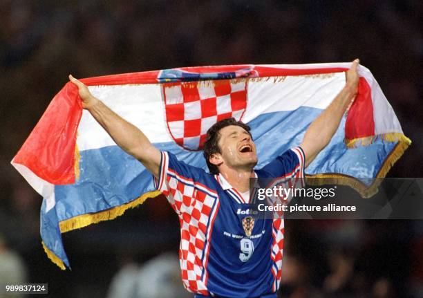 Croatian forward Davor Suker cheers and jubilates while he walks across the pitch holding the Croatian national flag in his hands after Croatia wins...