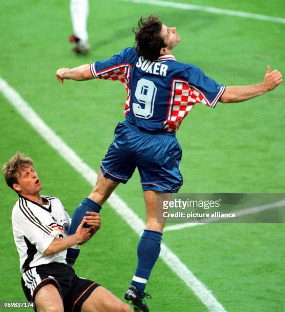 German defender Christian Woerns holds on to the leg of Croatian forward Davor Suker in a duel for the ball during the 1998 World Cup quarter final...