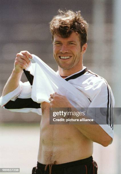 German team captain and midfielder Lothar Matthaeus pulls up his tricot and smiles during a training session of the German national soccer team in...