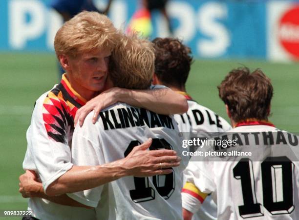 German midfielder Stefan Effenberg , midfielder and team captain Lothar Matthaeus and forward Karlheinz Riedle congratulate their forward Juergen...