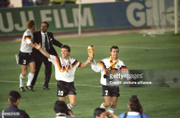 German midfielder and team captain Lothar Matthaeus and German forward Pierre Littbarski wear their medals, cheer, smile while they walk a lap of...