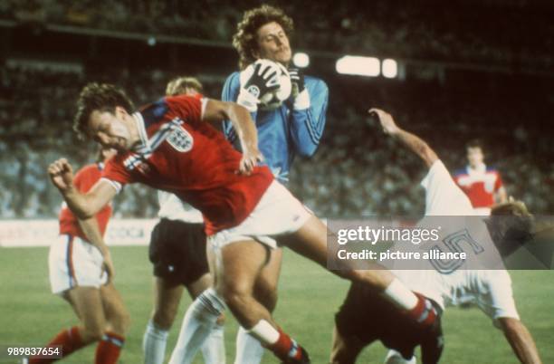 German goalkeeper Harald "Toni" Schumacher catches the ball before English midfielder Bryan Robson and his own defender Bernd Förster . The German...