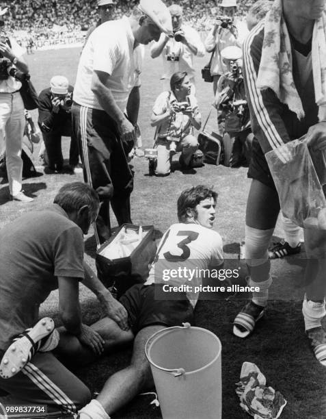 German forward Gerd Mueller lies on his belly on the pitch and receives a massage on his left thigh from team masseur Erich Deuser while soccer coach...