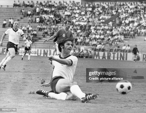 German forward Gerd Mueller slides on the pitch and manages to kick the ball while his fellow teammate German forward Uwe Seeler and Moroccan player...