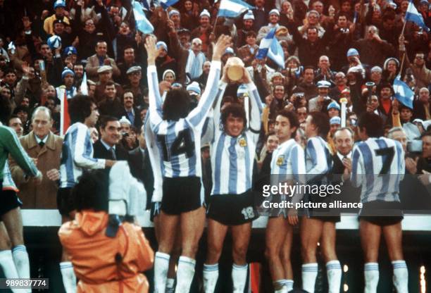 Daniel Passarella , captain of the Argentinian national soccer team, holds the World Cup trophy triumphantly in his hands. His teammates Leopoldo...