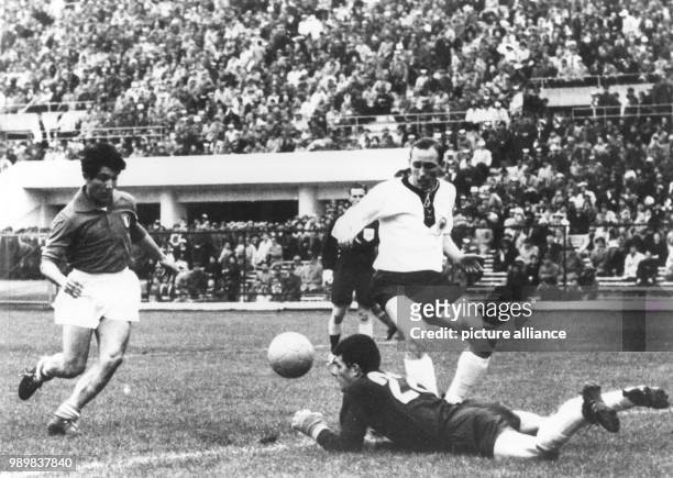 German goalkeeper Wolfgang Fahrian dives for the ball before Italian forward Omar Sivori can get to it, while German defender Willi Schulz tries to...
