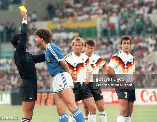 Argentinean forward Gustavo Dezotti is booked after a foul against his German opponent Pierre Littbarski . Fellow Germans Andreas Brehme and Lothar...