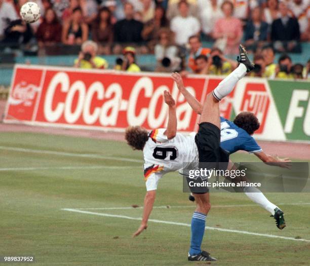 German forward Rudi Voeller and his Argeninean opponent Oscar Ruggeri seem to perform a pirouette as they fight for the ball. The German national...