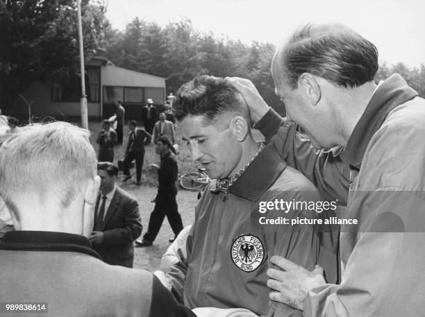 Assistant coach Helmut Schoen is running his hand over the new hairdo of player Helmut Rahn after winning the 1958 FIFA World Cup preliminary round...