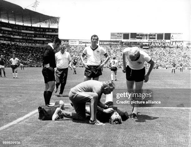 German goalkeeper Sepp Maier is injured, lying on the ground and is treated by physiotherapist Erich Deuser. Maier's teammates Karl-Heinz...