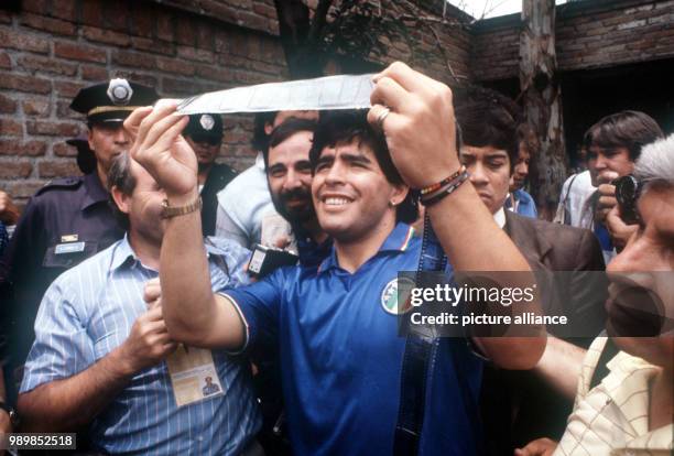 Diego Maradona, Argentina's midfield star, goalgetter and team captain, is looking at film footage amidst a group of photographers in Mexico City....