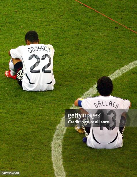 German players David Odonkor and Michael Ballck sit on the ground after Italy after extra time in the semi final of the 2006 FIFA World Cup between...