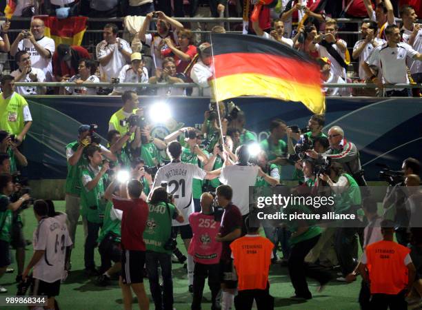 Amidst the photographers, German players are flying the national flag. Germany won the 3rd place match against Portugal during the 2006 FIFA World...