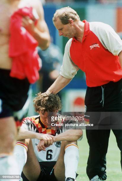 German team coach Berti Vogts is comforting the deeply disappointed defender Guido Buchwald who sits on the grass. Germany lost 1:2 in the quarter...