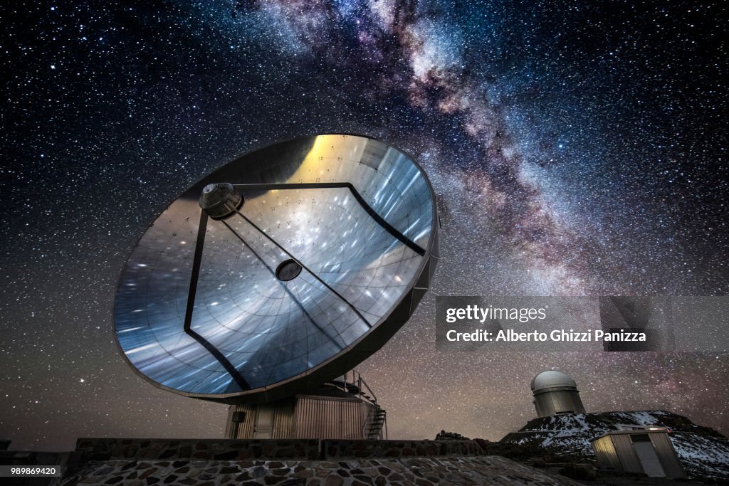 A satellite and telescope under the Milky Way.