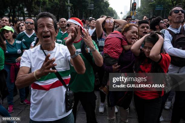 Fans of Mexico react as they watch the World Cup football match between Mexico and Brazil during a public event at the Angel de la Independencia...