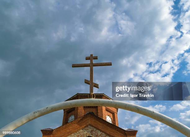 white semi-circular arch of iron pipe with dark orthodox cross over it before the tower - iron cross stock pictures, royalty-free photos & images