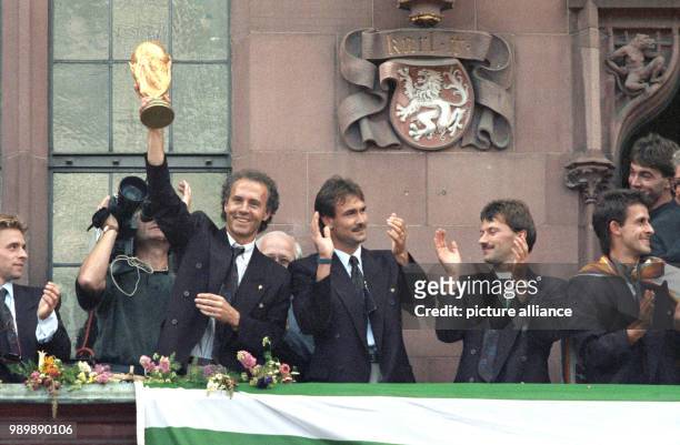 Team manager Franz Beckenbauer is holding up the World Cup trophy on the balcony of Frankfurt's town hall, the Roemer; Raimond Aumann, Guenther...