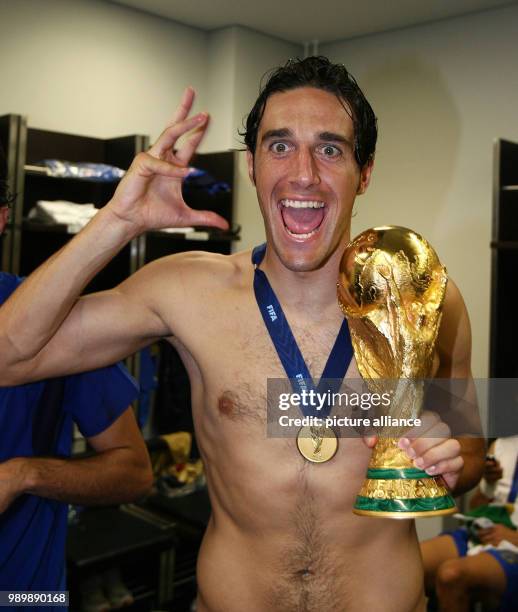 Italy's national team is celebrating the World Cup title in the dressing room, Luca Toni holding the World Cup trophy.