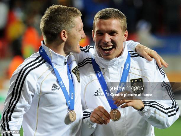 Bastian Schweinsteiger and Lukas Podolski of Germany celebrates with the bronze medal after the 2010 FIFA World Cup third place match between Uruguay...