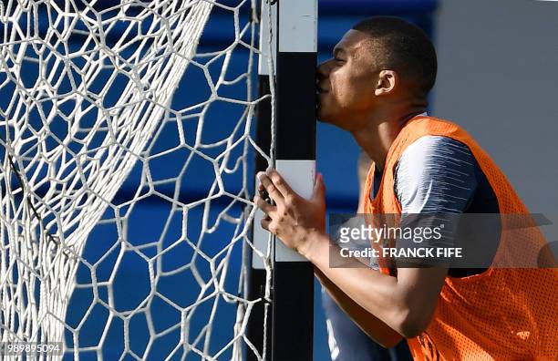 France's forward Kylian Mbappe kisses a goal post during a training session at the Glebovets stadium in Istra, some 70 km west of Moscow on July 2...