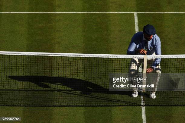 An official checks the height of the net during the Men's Singles first round match between Stanislas Wawrinka of Switzerland and Grigor Dimitrov of...