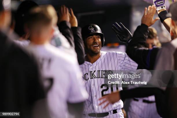 Ian Desmond of the Colorado Rockies celebrates with teammates in the dugout after hitting a home run during a game against the New York Mets at Coors...