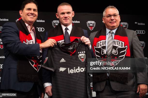 United's new recruit British footballer Wayne Rooney poses with DC United CEO Jason Levien and General Manager Dave Kasper at a press conference in...