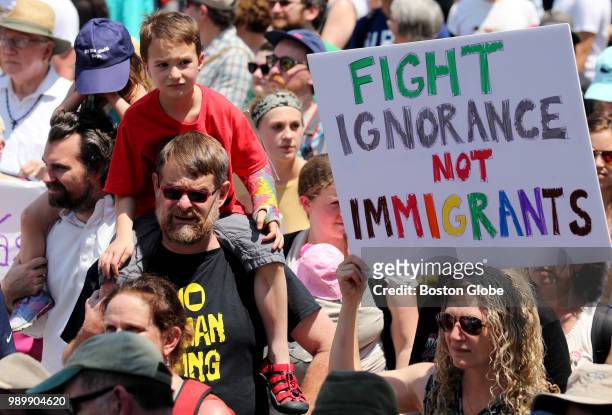 Demonstrators carry signs during the Together and Free Rally Against Family Separation in Boston on June 30, 2018. Thousands of demonstrators marched...