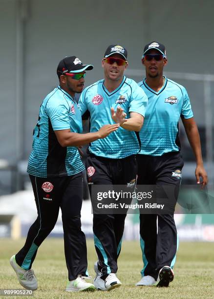 David Warner of Winnipeg Hawks celebrates with Junaid Siddiqui and Lendl Simmons after catching out Nizakat Khan of Toronto Nationals during a Global...