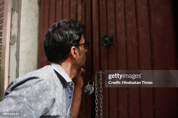 Man peeps inside the house where 11 members of the Bhatia family allegedly committed suicide, at Burari on July 2, 2018 in New Delhi, India. A day...