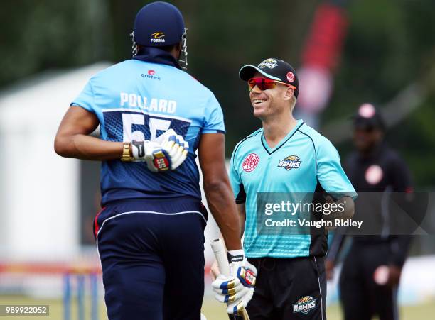 David Warner of Winnipeg Hawks laughs with Kieron Pollard of Toronto Nationals after Pollard was hit in the back with a ball in a Global T20 Canada...