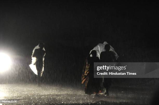 People cover themselves with plastic sheets during rainfall on July 2, 2018 in Noida, India. Heavy rain lashed parts of Delhi and the National...