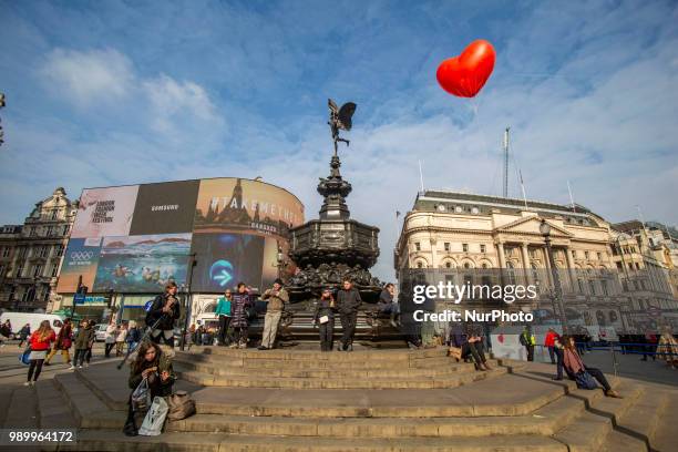 Tourists and locals walking in Piccadilly Circus or sitting on the steps of the Shaftesbury Memorial Fountain in Piccadilly Circus in City of...