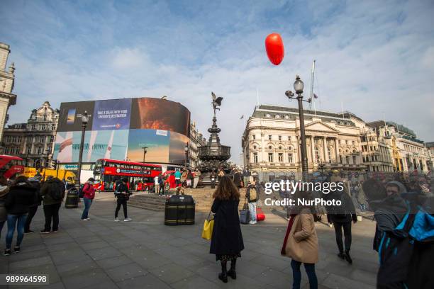 Tourists and locals walking in Piccadilly Circus or sitting on the steps of the Shaftesbury Memorial Fountain in Piccadilly Circus in City of...