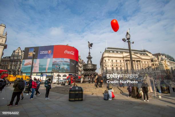 Tourists and locals walking in Piccadilly Circus or sitting on the steps of the Shaftesbury Memorial Fountain in Piccadilly Circus in City of...